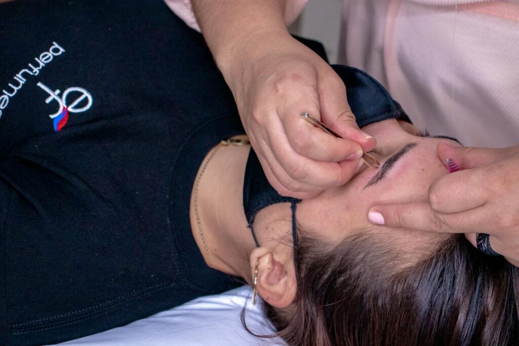 Close-up of a woman receiving eyebrow styling at a spa, highlighting beauty treatment process.