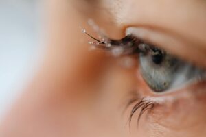 Close-up macro photograph of a blue eye with frosted eyelashes, reflecting a winter theme.