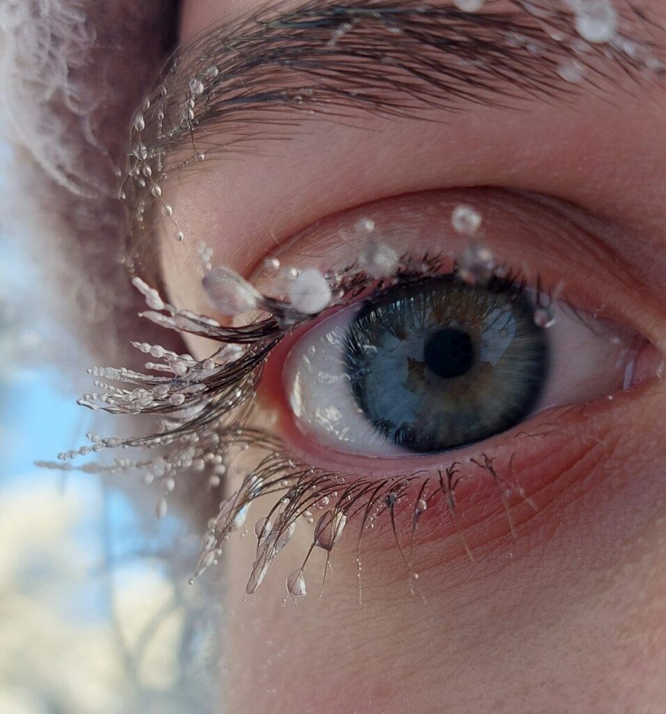 A close up of a person's eye with snow on it