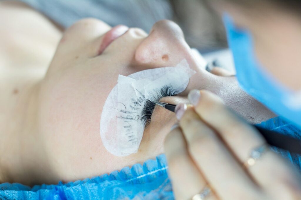 a woman getting her eyelashes done by a professional makeup artist