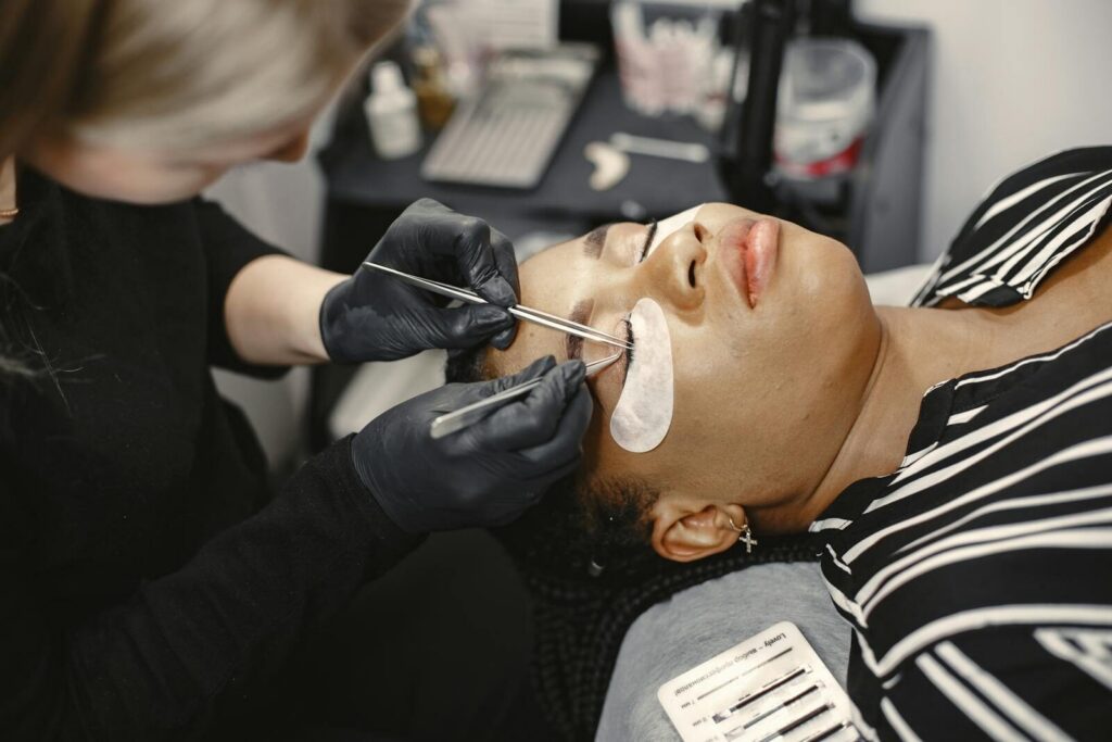 Beauty treatment with a technician applying eyelash extensions to a client in a salon setting.